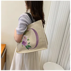 Detailansicht der Jute-Tragetasche mit lila Blumendruck und robusten schwarzen Schultergurten