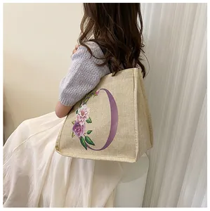 Detailaufnahme der Jute-Tragetasche mit Blumenmuster und lila Buchstaben-Aufdruck