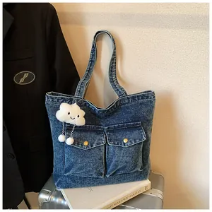 Detail of blue denim tote bag with functional front pockets and plush cloud charm
