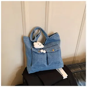 Close-up of blue denim tote bag featuring front pockets and a cute cloud charm