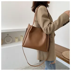 Detailed side view of a large brown leather tote bag with dual straps on a model