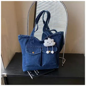 Detail of blue denim tote bag with brass buttons and a white cloud plush charm