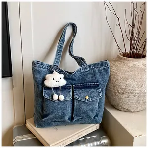 Macro detail of large denim tote bag with cargo pockets and a cute cloud plush charm