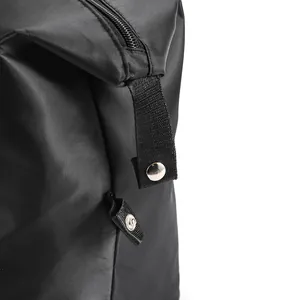 Detail of waterproof black travel bag showing nylon texture and silver button on strap