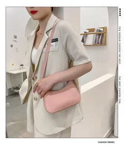 Chic pink leather underarm bag held by model wearing a stylish cream-white blazer