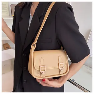 Close-up of minimalist beige PU leather shoulder bag with decorative buckle and rivets