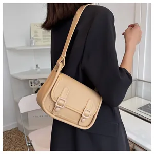 Beige faux leather crossbody bag worn by a model with a dark blazer and double straps