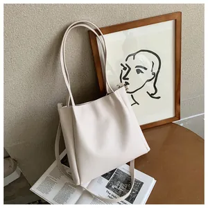 Detail shot of a cream PU leather tote bag with dual handles and long shoulder strap