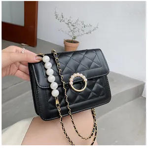 Detail of black quilted crossbody bag featuring pearl ring buckle and chain strap