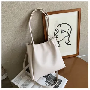 Detail view of cream faux leather tote bag with pleated sides and adjustable shoulder straps