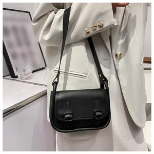 Detail of a black vintage minimalist crossbody bag shown with a cream-colored blazer