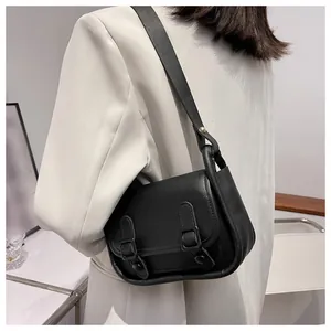 Close-up of a black retro satchel with double buckle straps and a wide shoulder strap