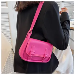Detailed view of magenta small square shoulder bag with double buckle straps on a model