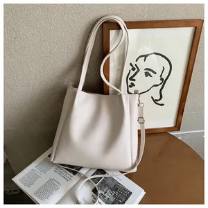 Minimalist beige PU tote bag on a wooden table with magazines in a stylish setting