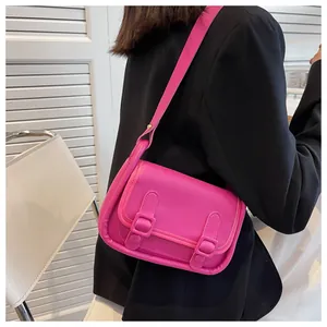 Detail of a bright pink crossbody bag showing the leather texture and buckle design