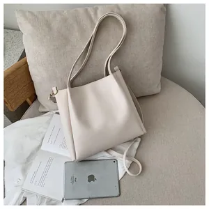 Close-up of a beige faux leather tote bag with dual straps and metallic buckle detail