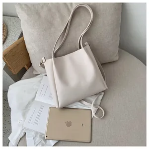 Detail of a large cream leather tote bag on a grey sofa with lifestyle accessories