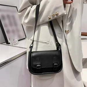 Chic black vintage crossbody bag with dual buckles shown in a minimalist setting