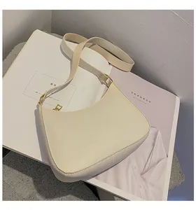 Detail of minimalist cream half-moon underarm bag with gold zipper on a fashion magazine