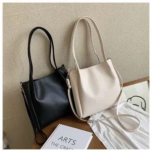 Detail view of large capacity tote bags in black and beige with smooth PU leather finish