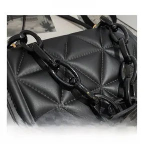 Detailed close-up of black quilted shoulder bag with chic chunky chain texture