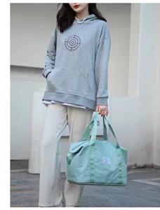 Detail of mint green travel bag with reinforced handles and waterproof fabric finish