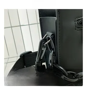 Close-up of black crossbody bag with detachable metal hooks and textile shoulder strap