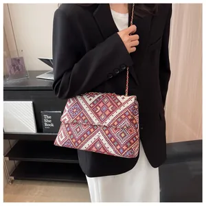 Detail of retro geometric woven shoulder bag with golden chain strap on a model