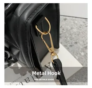 Close-up of premium gold hardware hook on black quilted shoulder bag detail
