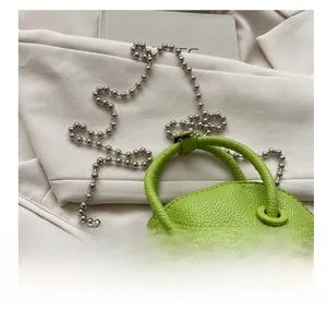 Detailed view of neon green litchi texture mini shell bag with silver ball chain
