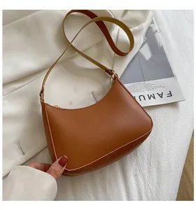 Chic caramel brown crescent shoulder bag on a minimalist white fabric background