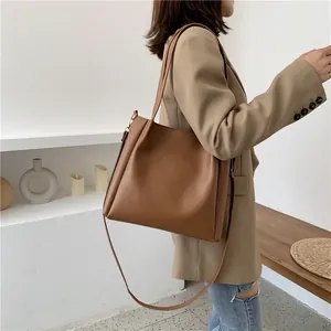Minimalist brown leather tote bag with adjustable strap shown in a modern home setting