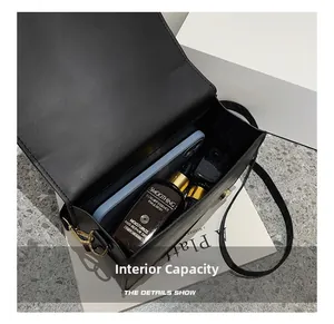 Internal capacity of the black shoulder bag showing phone and cosmetics inside