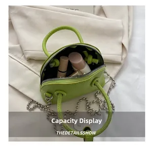 Internal view of green lychee leather mini shell bag holding lipstick and makeup samples
