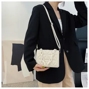 Detail of cream quilted crossbody bag featuring a thick acrylic chain and PU leather texture