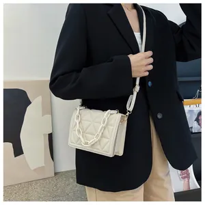 Detail of cream quilted crossbody bag with acrylic chain and adjustable leather strap