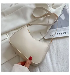 Detailed close-up of cream textured leather underarm bag with gold zipper and strap