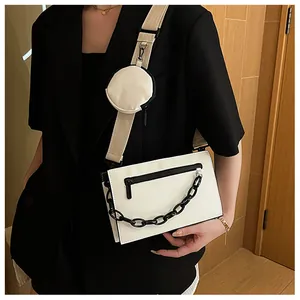 Detail of white envelope crossbody bag with black chain and round coin purse attachment