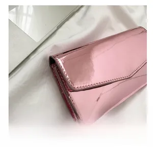 Detail of pink mirror-finish card holder clutch with metallic texture and fine stitching