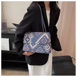 Close-up of geometric woven pattern and gold chain strap on the shoulder tote bag