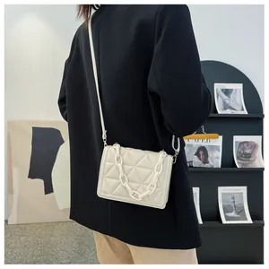 Detail of quilted crossbody bag with thick acrylic chain strap on model's shoulder