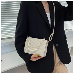 Close-up of white quilted crossbody bag with stylish acrylic chain and long strap