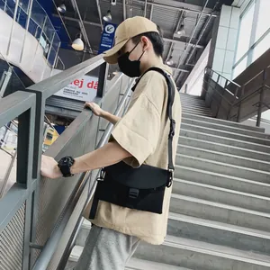 Photo en extérieur d'un homme portant une sacoche noire en nylon avec sangle réglable
