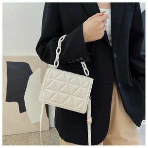 Detailed close-up of a cream crossbody bag featuring quilted texture and acrylic chain