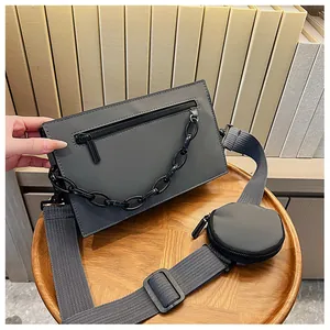 Detail of grey envelope crossbody bag featuring a chunky black chain and small round coin purse