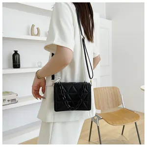 Detail of black quilted PU leather shoulder bag with chunky acrylic chain and adjustable strap