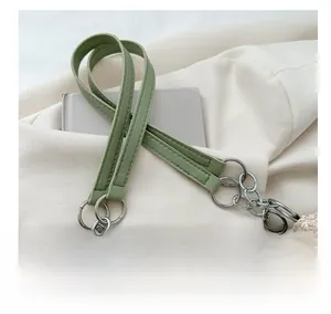 Detail view of the green leather and silver chain shoulder strap on straw tote bag
