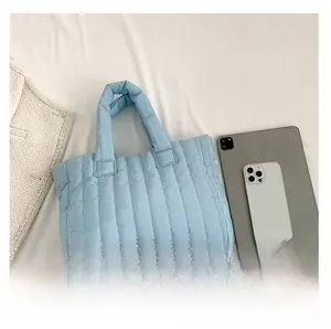 Détail du sac cabas matelassé bleu clair avec coutures verticales et poignées rembourrées
