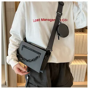 Detail of grey crossbody bag set with chain decor and round coin purse on shoulder strap
