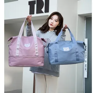 Pink and blue large travel bags with wet-dry separation held by a model outdoors